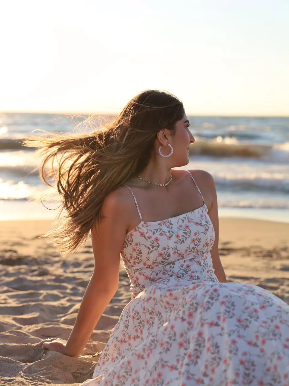 A girl in a floral dress on the beach at golden hour