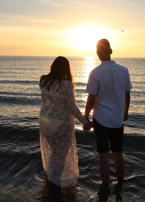 A couple holding hands in the lake at sunset